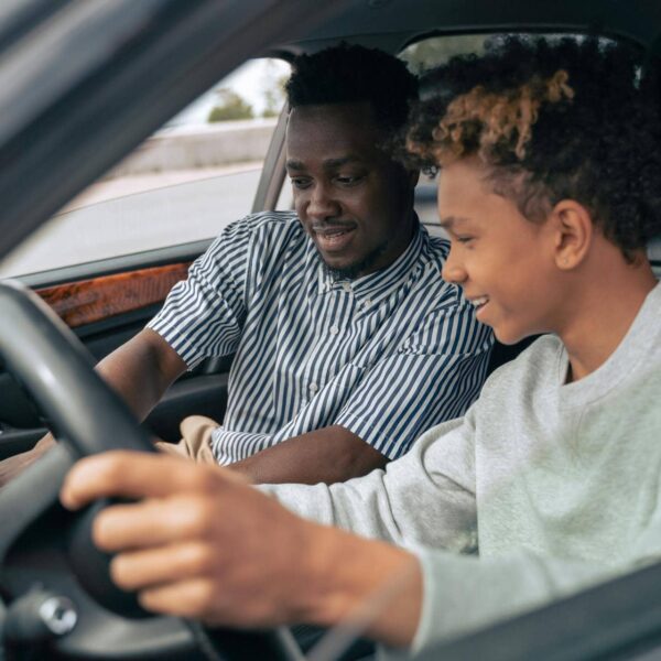 Symbolfoto für Anfängerfehler beim Autofahren – junger Fahrer im Auto mit konzentriertem Blick und Verkehrssituation