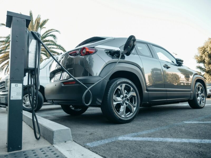 Symbolfoto: Mitarbeitende laden ein Elektroauto an einer Ladesäule des Unternehmens auf