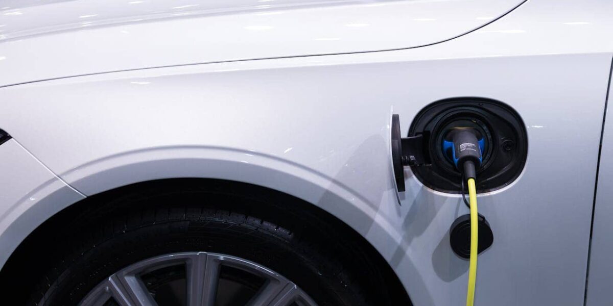 Nahaufnahme eines Kfz-Mechanikers beim Reparieren eines Elektroautos in einer Werkstatt