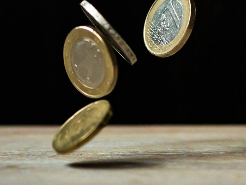einige eurobanknoten und münzen auf einer tischoberfläche vor auto