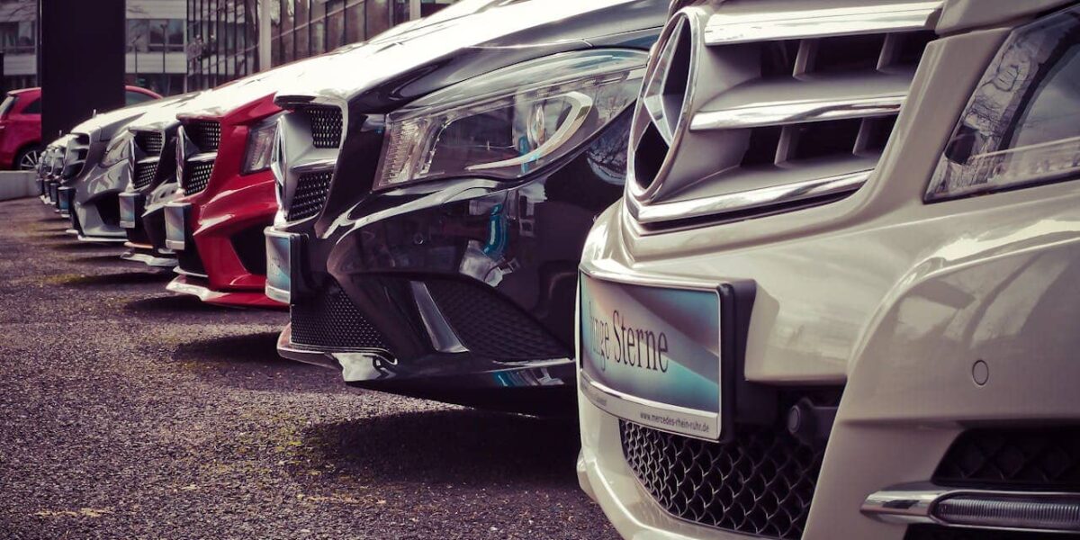 Ein Mann betrachtet verschiedene Autos in einem Autohaus und vergleicht die Vorteile von Privatleasing gegenüber Gebrauchtwagen.