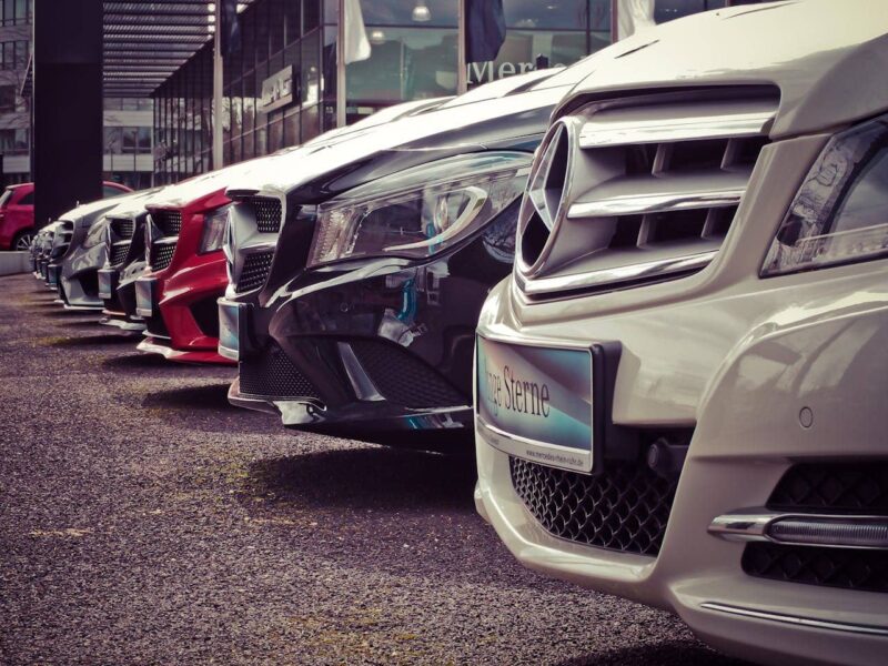 Ein Mann betrachtet verschiedene Autos in einem Autohaus und vergleicht die Vorteile von Privatleasing gegenüber Gebrauchtwagen.