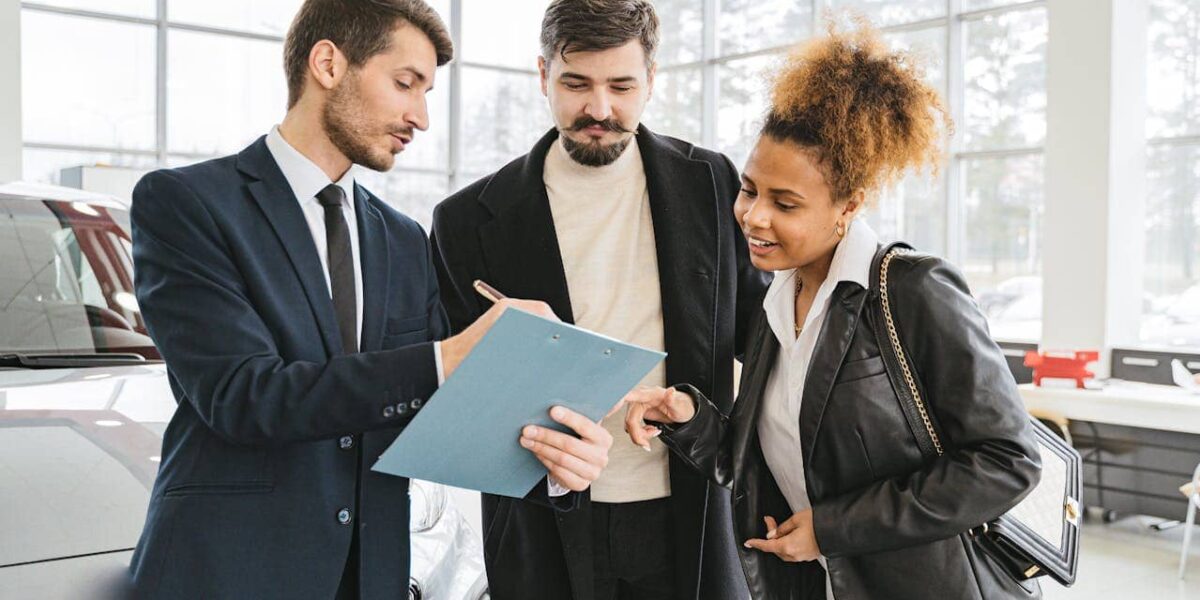 drei personen besprechen ein dokument am auto – pexels shkrabaanthony 7144181