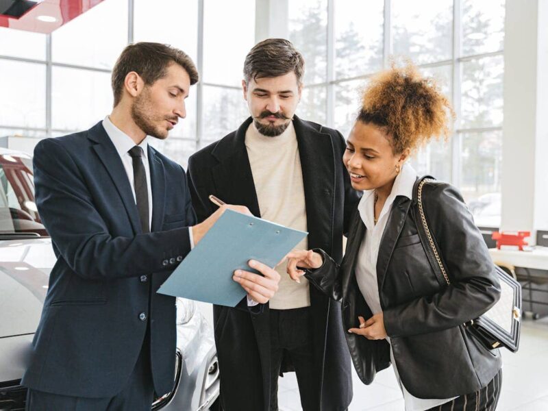 drei personen besprechen ein dokument am auto – pexels shkrabaanthony 7144181
