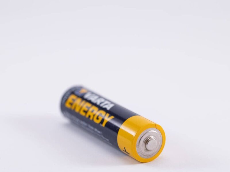 Nahaufnahme eines Autoschlüssels mit ausgebauter Knopfzellenbatterie auf einem neutralen Hintergrund