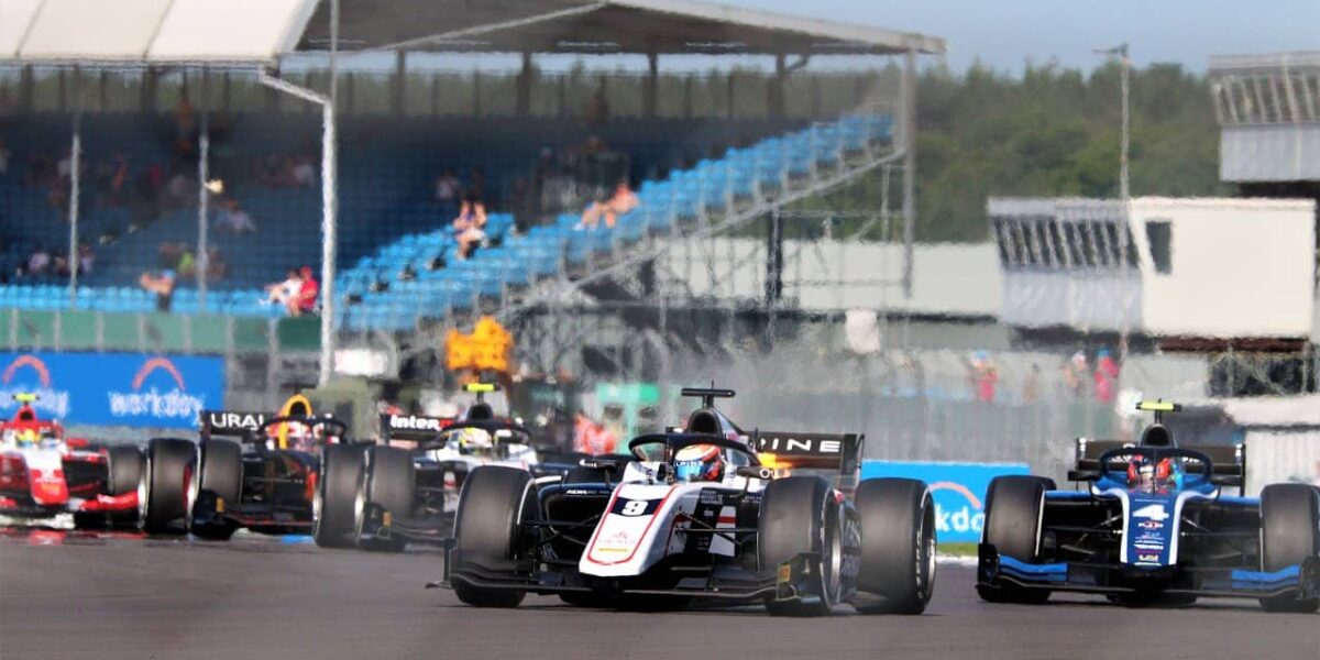 Formel-2-Auto auf der Rennstrecke mit Tribünen im Hintergrund