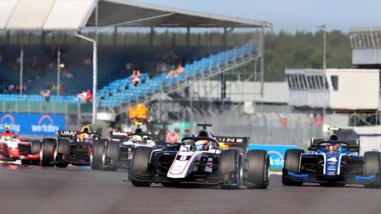 Formel-2-Auto auf der Rennstrecke mit Tribünen im Hintergrund