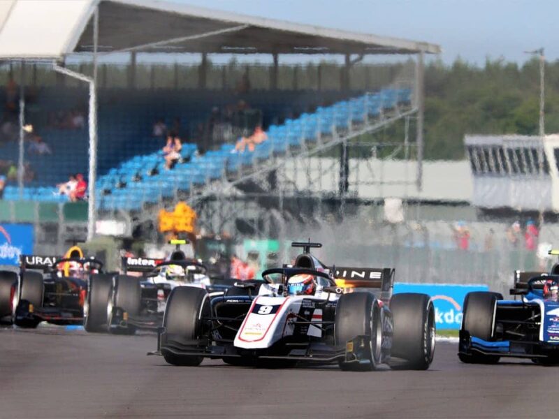 Formel-2-Auto auf der Rennstrecke mit Tribünen im Hintergrund