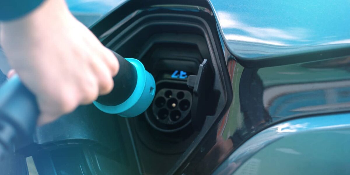 Mann steckt Ladekabel an Ladestation für Elektroauto ein