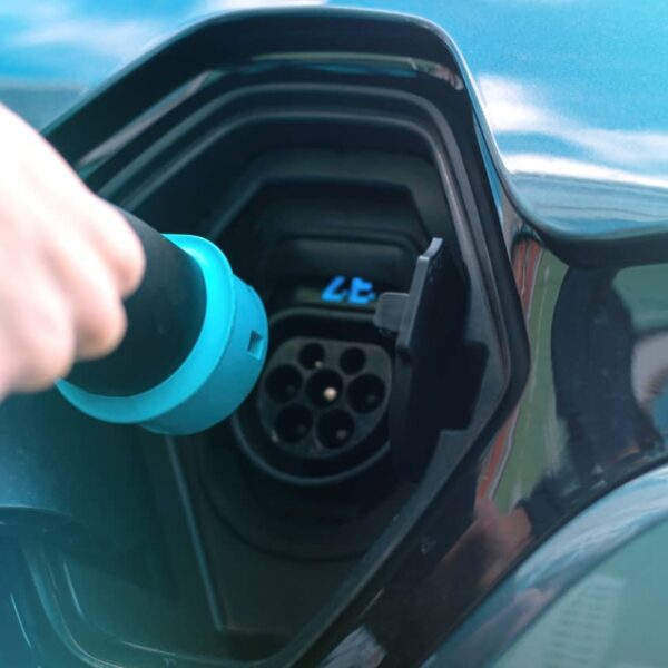 Mann steckt Ladekabel an Ladestation für Elektroauto ein