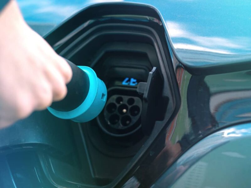 Mann steckt Ladekabel an Ladestation für Elektroauto ein