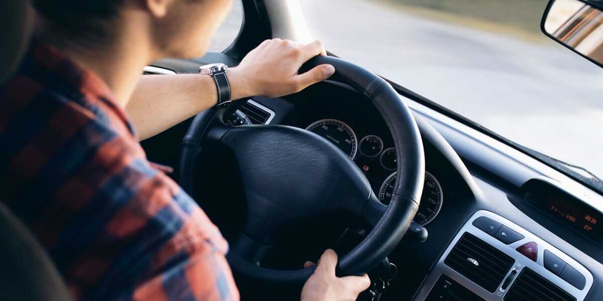 Junge Person am Steuer eines Autos (Symbolbild, Straßenverkehr, Führerschein, sicher fahren).