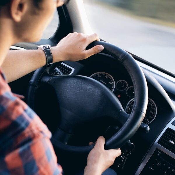 Junge Person am Steuer eines Autos (Symbolbild, Straßenverkehr, Führerschein, sicher fahren).