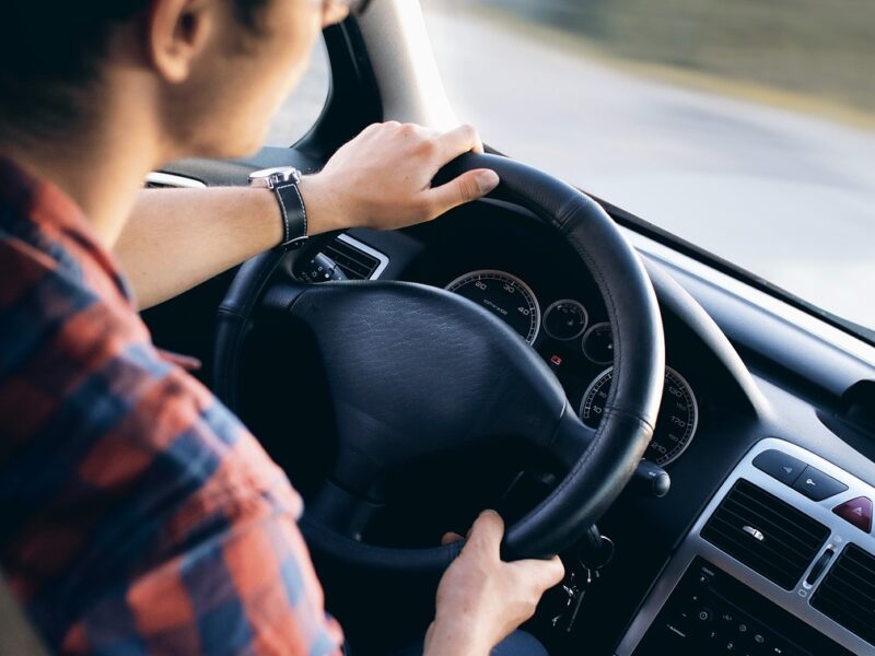 Junge Person am Steuer eines Autos (Symbolbild, Straßenverkehr, Führerschein, sicher fahren).