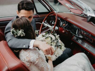 Brautpaar steigt am Hochzeitstag in ein Hochzeitsauto mit festlicher Dekoration ein