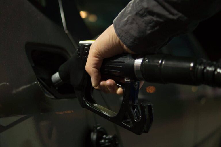 Gasoline pump nozzle at a station in the Netherlands with posted price sign
